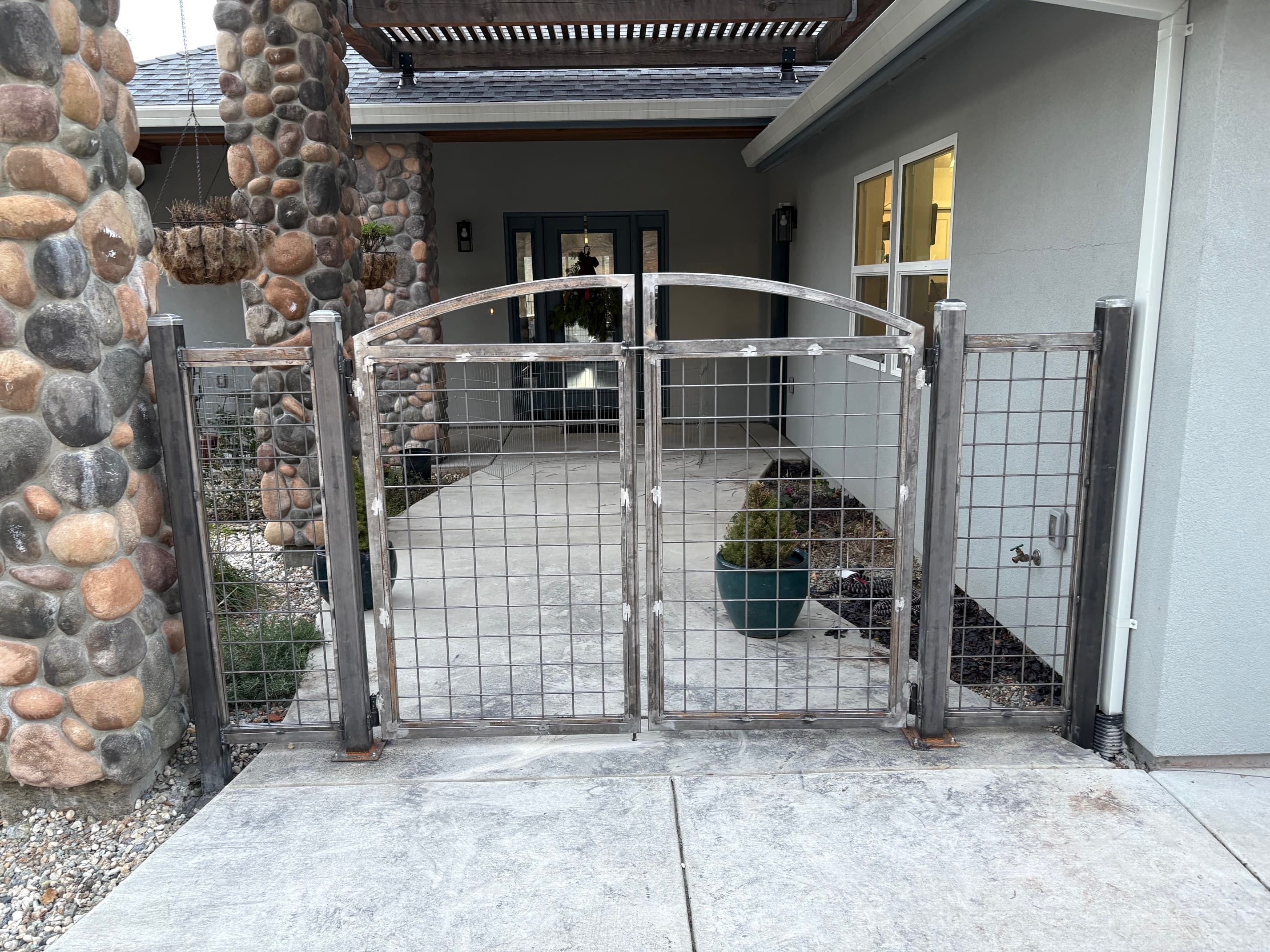 Custom arched double gate with wire infill between stone columns